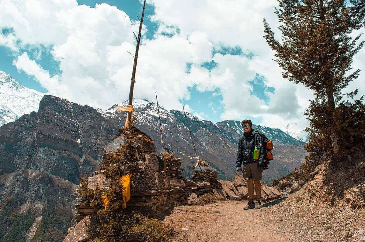 Annapurna Circuit Itinerary: All You Need To Know About The Best Trek In Nepal 19 james hiking the annapurna circuit with snowy mountains in the backdrop