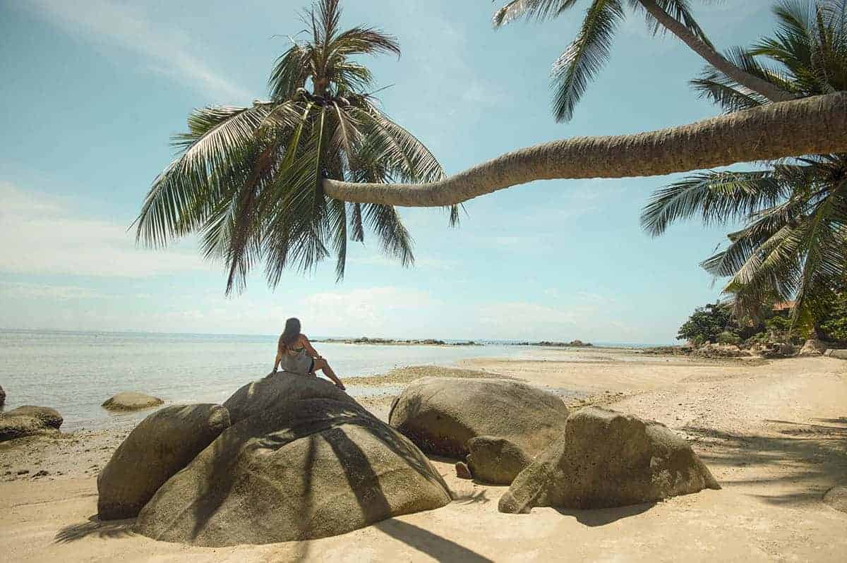 Cost To Travel Thailand: How I Spent $23 Per Day 18 relaxing on the beach at koh phangan under the shade of a palm tree