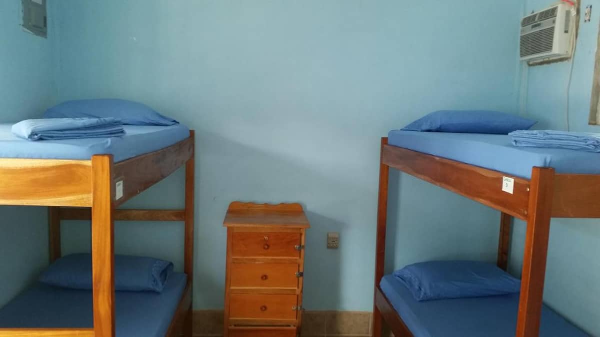 Hostels In Caye Caulker: BEST Stays For Backpackers 6 the dorm rooms at go slow hostel in caye caulker with the air conditioning unit up in the corner