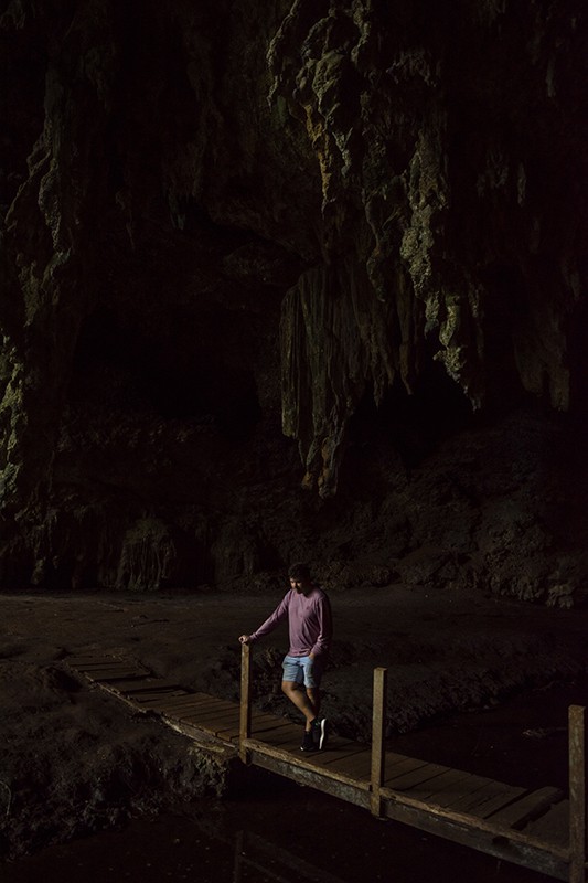 A man standing on a wooden bridge in front of Queen Hortense’s Cave on the Isle Of Pines.
	