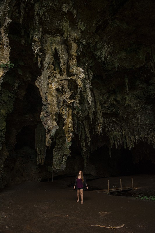 A woman standing in front of Queen Hortense’s Cave on the Isle Of Pines.
	
