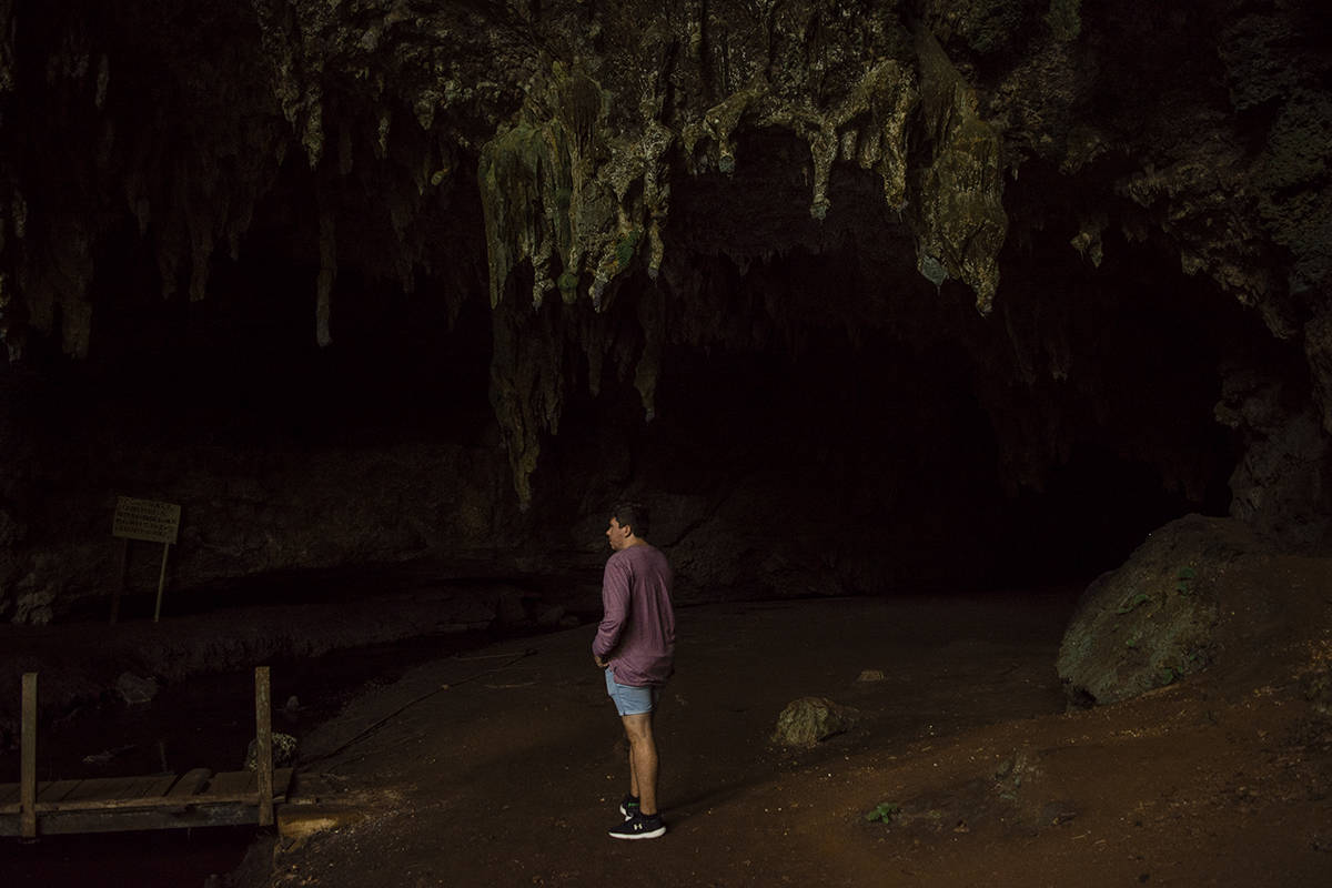 A man standing in front of Queen Hortense’s Cave on the Isle Of Pines.
	