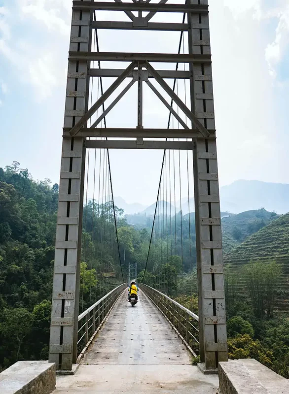 3 Week Vietnam Itinerary: BEST North To South Route 12 Solitary motorcyclist on a bridge in the mountainous regions of Vietnam, a journey to remember on a 3 week Vietnam adventure.