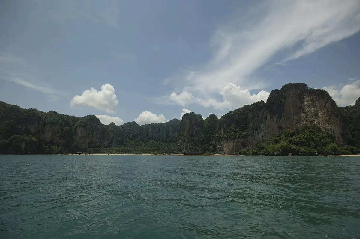 Ao Nang To Railay Beach: The ULTIMATE Guide 2025 5 Panoramic seascape showing the coastline of Railay Beach with jungle and cliffs rising from the water.