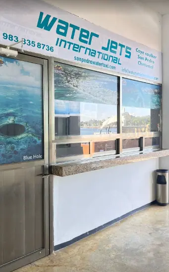 Bacalar To Caye Caulker: The ULTIMATE Travel Guide 2025 6 The Water Jets International ticket office, providing ferry services to Caye Caulker, San Pedro, and Chetumal. The office features a sign with contact details and a promotional image of the Blue Hole.
