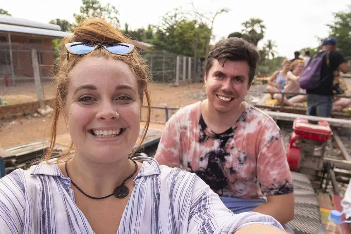 Battambang Bamboo Train: Is It Still Worth Visiting? 2025 16 tasha amy takes a selfie on a bamboo train in Battambang. In the background is some other travelers and a few carts.