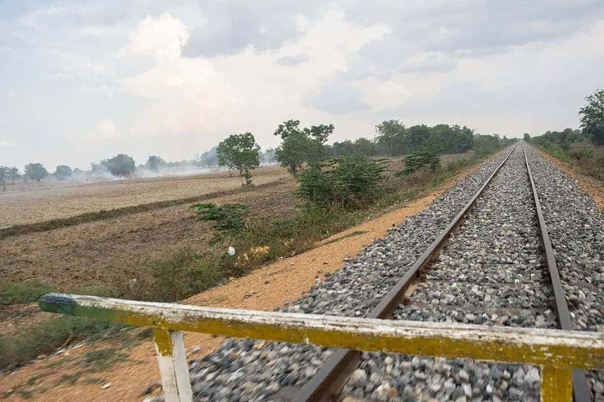 Battambang Bamboo Train: Is It Still Worth Visiting? 2025 13 View from the battambang bamboo train looking down a long stretch of rocky rail track cutting through dry Cambodian farmland.