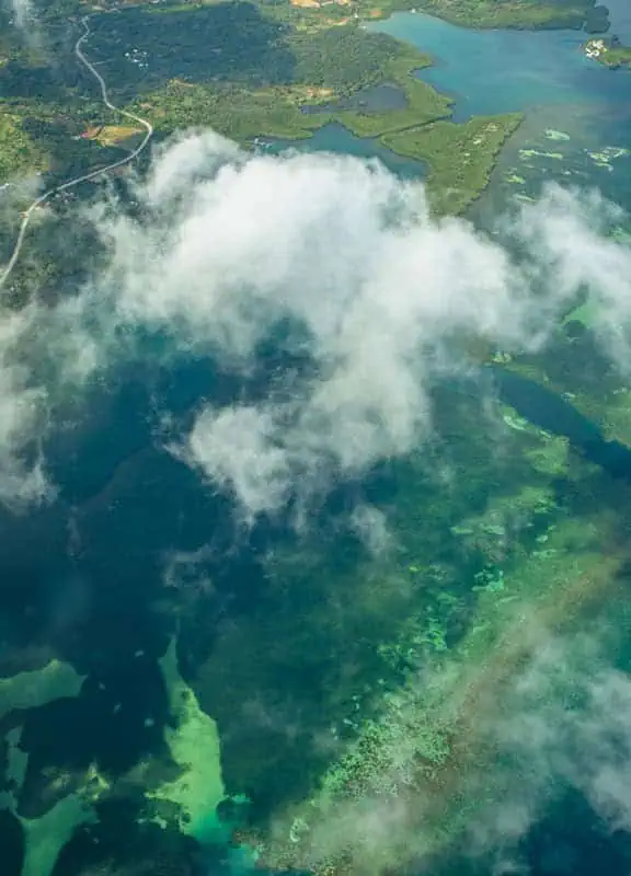 Aerial view of the Belize Barrier Reef cloaked in clouds, a remarkable natural wonder observed on flights from Belize City to Caye Caulker.