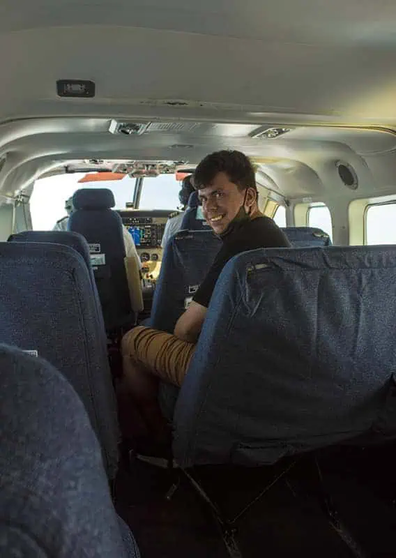 Inside a small aircraft, a passenger smiles back, indicative of the short and scenic flights available from Belize City to Caye Caulker.
