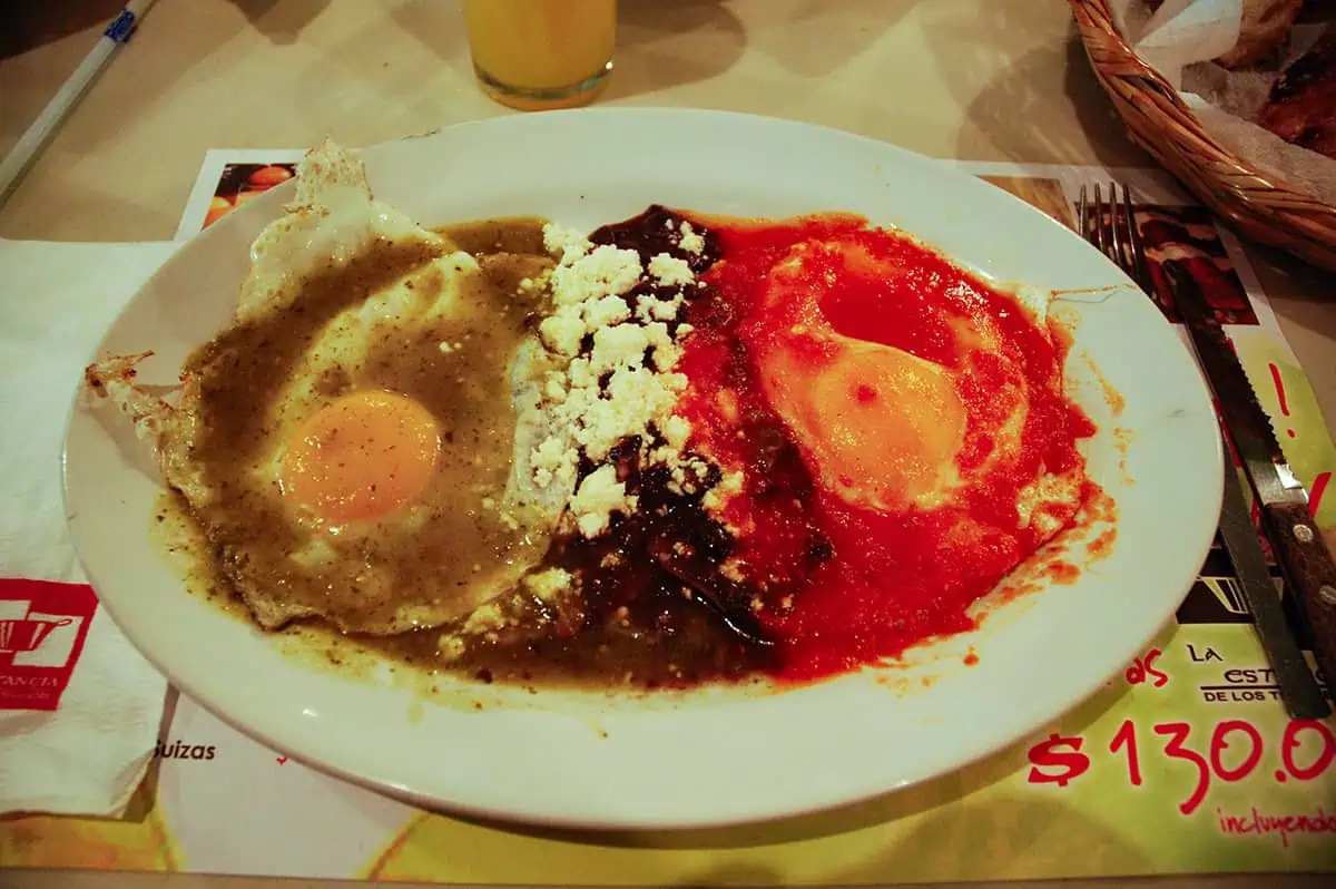 A hearty plate of huevos rancheros, a classic breakfast in Belize, featuring fried eggs atop a bed of black beans and cheese, smothered with red sauce
