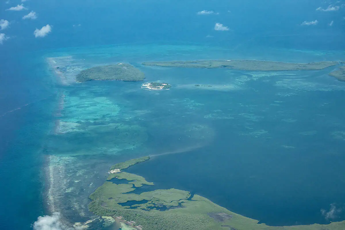 This image presents a more detailed view of an atoll in Belize, where various shades of blue and green highlight the diverse underwater ecosystem and the atoll's complex structure.