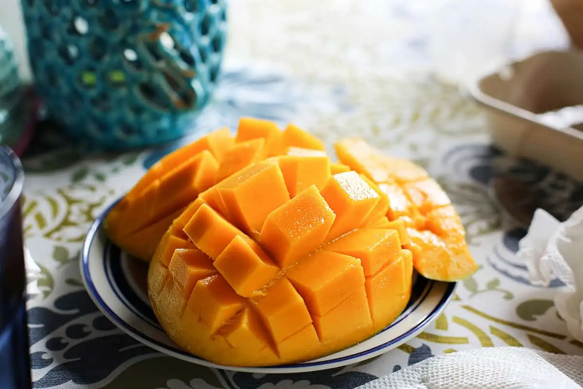 Fruits In Belize: The BEST 24 Fruits Worth Trying On Your Visit 5 A ripe mango artfully cut in a grid pattern on a plate, ready to be enjoyed, showcasing a popular way to eat this sweet fruit.