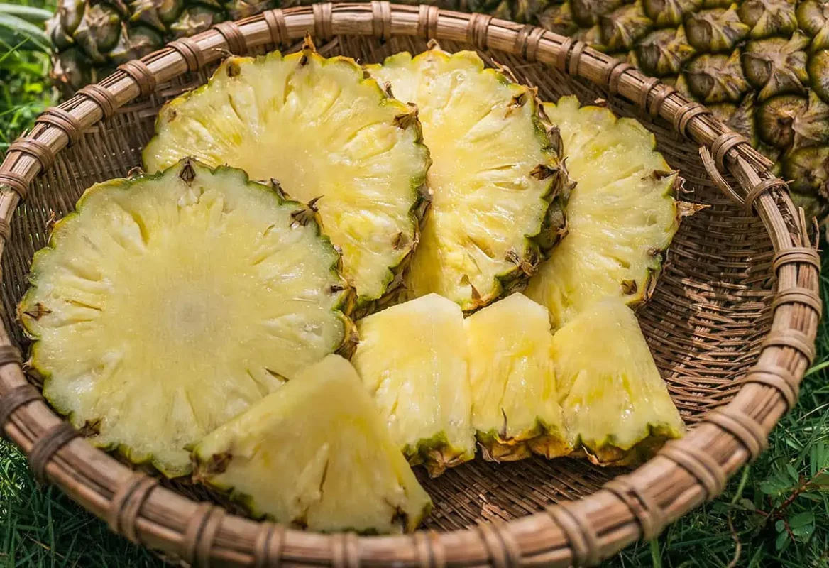 Fruits In Belize: The BEST 24 Fruits Worth Trying On Your Visit 9 Freshly cut pineapple slices arranged in a woven basket, emphasizing the juicy, tropical flavor.