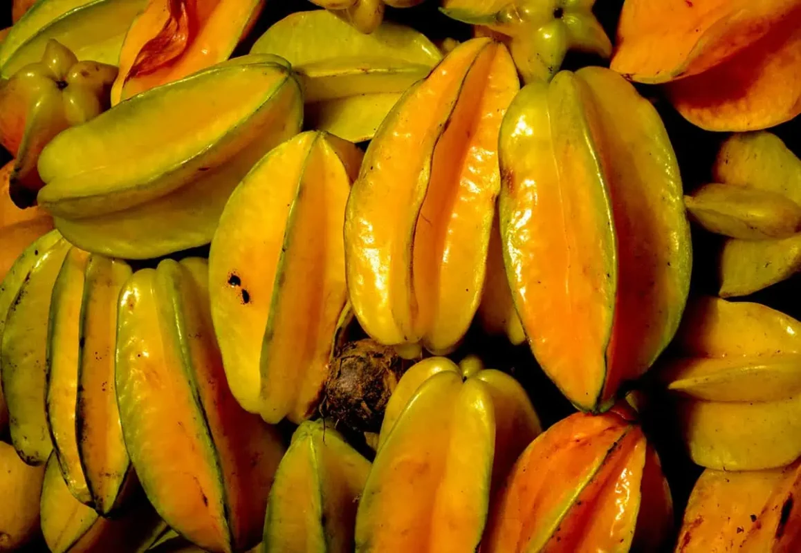 Fruits In Belize: The BEST 24 Fruits Worth Trying On Your Visit 13 Pile of yellow-orange star fruits, also known as carambola, a tropical fruit that is commonly enjoyed in Belize for its sweet and tangy flavor.