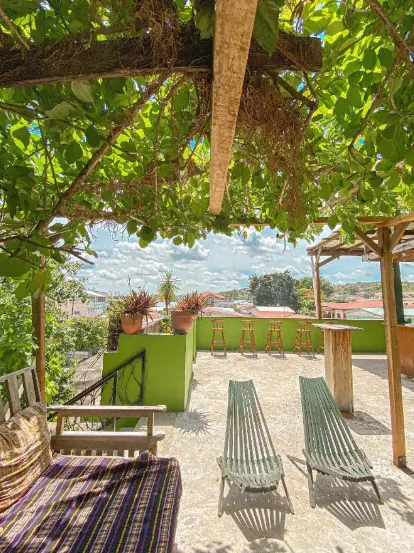 Best Hostels In San Ignacio: 5 Excellent Stays For Travelers On A Budget 11 A sunny rooftop terrace at Bella's Backpackers, displaying comfortable seating and lush greenery, inviting guests to relax and socialize in one of San Ignacio's top hostels.