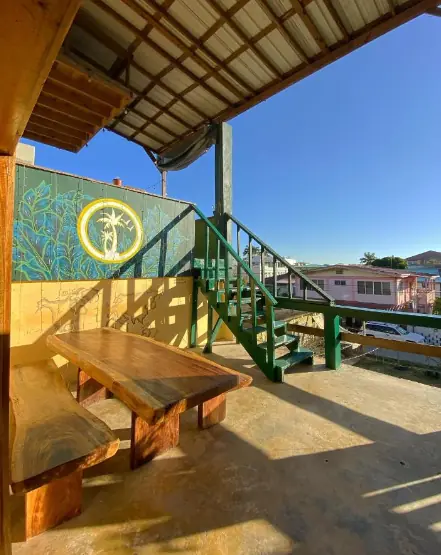 Best Hostels In San Ignacio: 5 Excellent Stays For Travelers On A Budget 12 A view of Bella's Backpackers' outdoor seating area with wooden benches and a mural, exemplifying the creative and inviting communal spaces at a leading San Ignacio hostel.