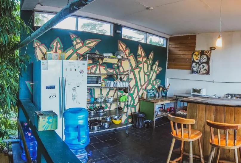 Best Hostels In San Ignacio: 5 Excellent Stays For Travelers On A Budget 13 A communal kitchen area inside Bella's Backpackers, adorned with colorful murals and fully equipped for guest use, illustrating the convenient facilities at this top-rated San Ignacio hostel.
