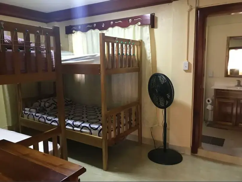 Best Hostels In San Ignacio: 5 Excellent Stays For Travelers On A Budget 10 Cozy and well-maintained dormitory room with wooden bunk beds and a standing fan, at D's Hostel, one of San Ignacio's comfortable accommodations.