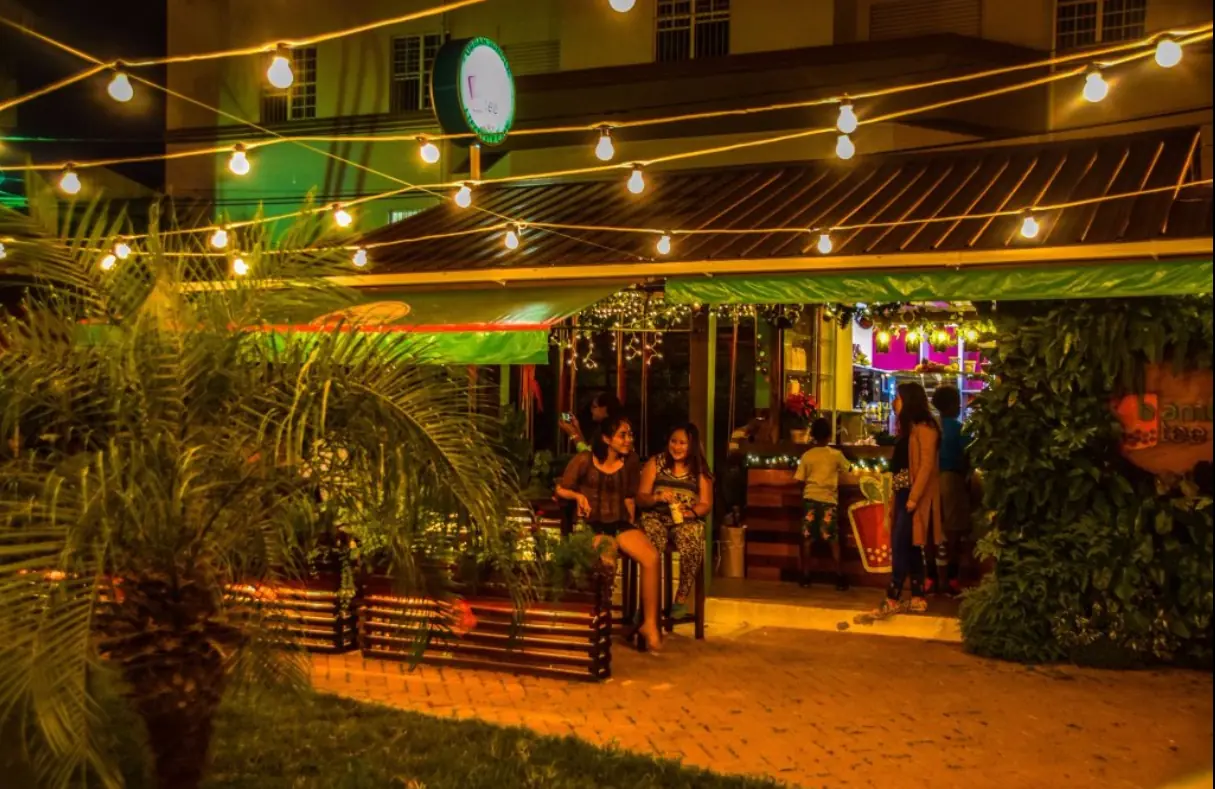 12 Best Restaurants In San Ignacio: Top Eats For Visitors 9 Warm, inviting ambiance of a restaurant at night with string lights, tropical plants, and guests dining al fresco, a cozy dining spot in San Ignacio.