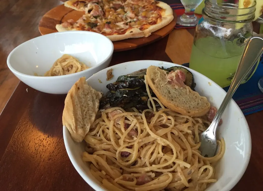 12 Best Restaurants In San Ignacio: Top Eats For Visitors 12 A laid-back meal setting with pasta, grilled vegetables, and a pizza in the background, typical of the relaxed dining atmosphere in guava limb cafe, one of the best restaurants in san ignacio