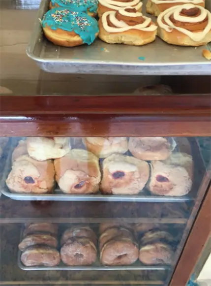 BEST Restaurants On Caye Caulker Worth Trying 2025 11 A glass bakery display case filled with a variety of sweet baked goods, including frosted cookies and rolls, in Caye Caulker bakery. The variety and appeal of these desserts highlight the island's culinary delights.