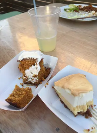 BEST Restaurants On Caye Caulker Worth Trying 2025 20 A casual dining setting at Chef Juan's Kitchen and Pastries featuring two popular desserts: a slice of carrot cake topped with cream cheese frosting and a slice of creamy pie, both served on paper plates. A cup of lemonade sits nearby, complementing the sweet treats, indicative of the relaxed yet indulgent dining experience at this Caye Caulker spot.