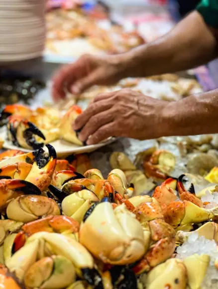 Best Restaurants In San Pedro Belize For Breakfast, Lunch & Dinner 11 A bustling scene at Caramba Restaurant in San Pedro Belize where a chef prepares a display of stone crab claws on ice, inviting diners to experience the fresh seafood that makes it one of the top restaurants in San Pedro Belize.