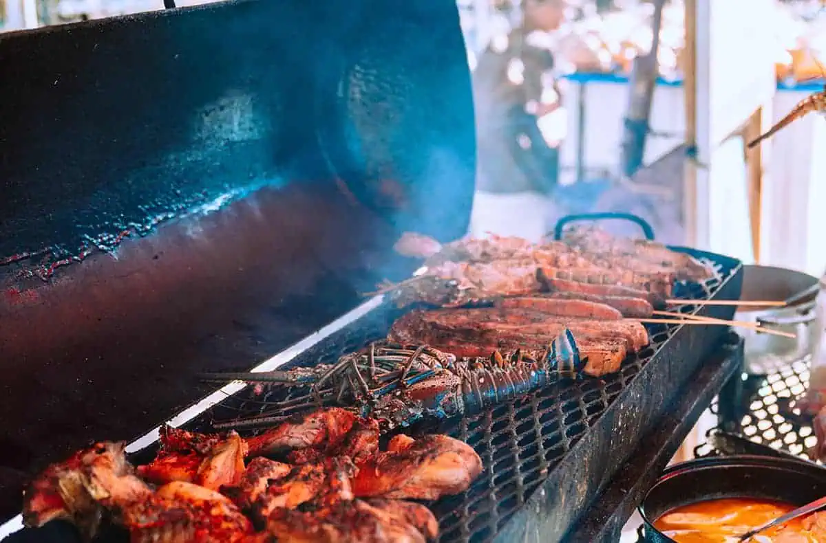 The 31 BEST Things To Do In Caye Caulker: Ultimate List! 27 A smoky barbecue grill loaded with various meats, including chicken and lobsters, with skewers of grilled vegetables. The open-air cooking setup adds to the island’s rustic charm. Having a barbecue is one of the best things to do in Caye Caulker, especially with fresh local seafood.