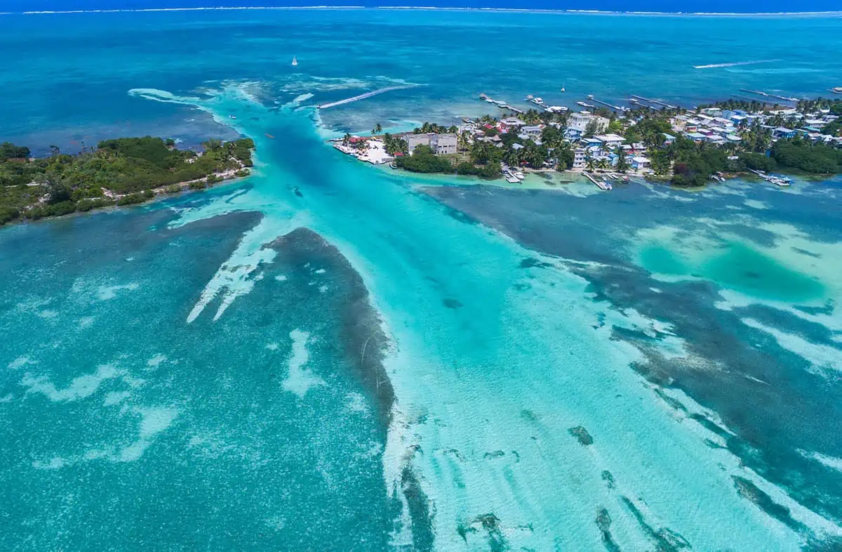 The 31 BEST Things To Do In Caye Caulker: Ultimate List! 28 An aerial photograph of Caye Caulker showing the striking split that divides the island, with lush greenery and clear, shallow waters in various shades of blue and green. Boats are docked along the shoreline, highlighting the island’s charm and natural beauty.