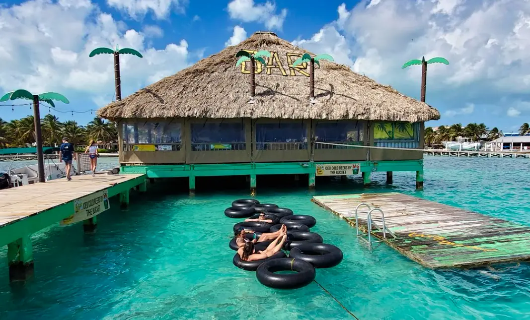 41 Best Things To Do In Ambergris Caye For The Ultimate Holiday 15 People floating on inner tubes near an overwater bar, capturing the fun and relaxing water activities available at Ambergris Caye.