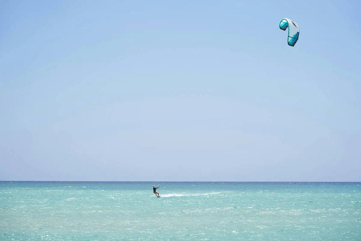 41 Best Things To Do In Ambergris Caye For The Ultimate Holiday 35 A kite surfer rides the gentle waves off the coast of Ambergris Caye, demonstrating the thrill and fun of one of the island's popular water sports against the backdrop of the clear blue sky.