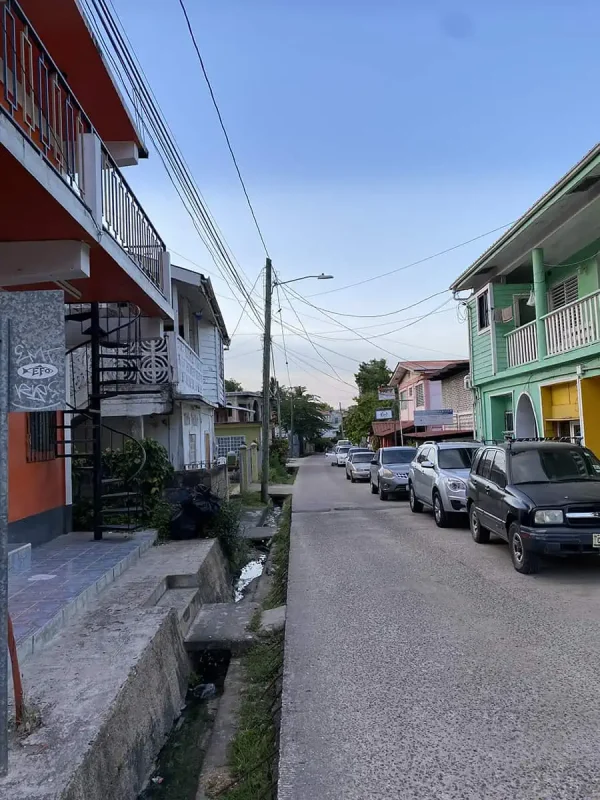 25+ Best Things To Do In San Ignacio, Belize (2025) 18 Another street view in San Ignacio, with pastel-colored buildings and a row of parked cars. The street appears calm and residential, highlighting the town's charm and everyday ambiance