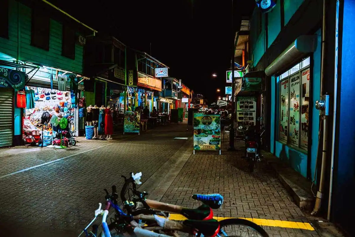 25+ Best Things To Do In San Ignacio, Belize (2025) 15 Night scene of a bustling street in San Ignacio, with brightly lit shops and vendors displaying their goods. The lively atmosphere and colorful storefronts showcase the vibrant local culture and one of the many things to do in San Ignacio.