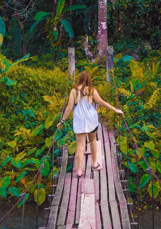 Blue Lagoon 3 In Vang Vieng: BEST Tips For Visiting 2025 14 climbing over a wooden bridge that leads to a cave at the blue lagoon in vang vieng