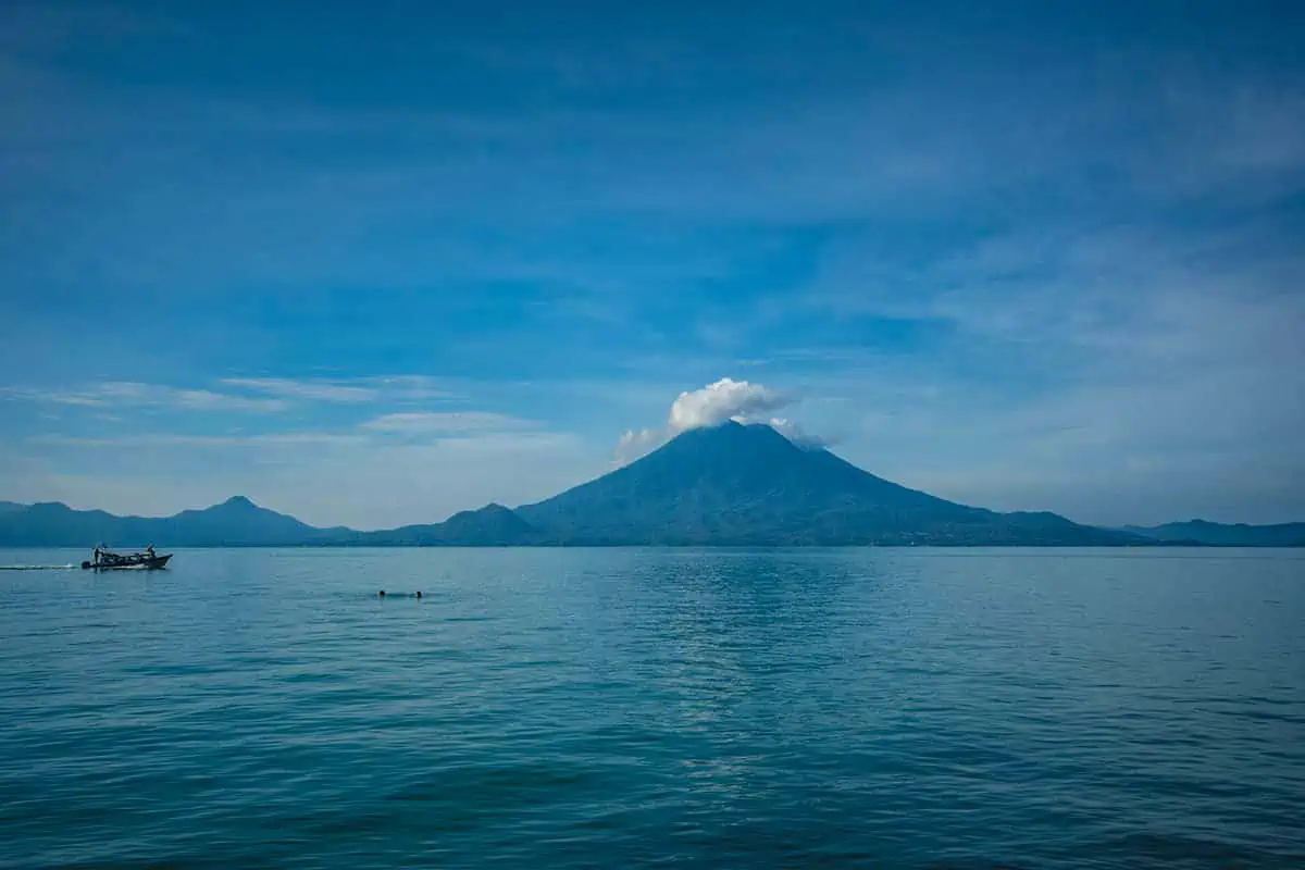 Can You Swim In Lake Atitlan Guatemala? The Water Quality, Sicknesses, & Sewage 7 looking over lake aititlan with two people braving the water, and water taxis, in front of santa cruz la laguna