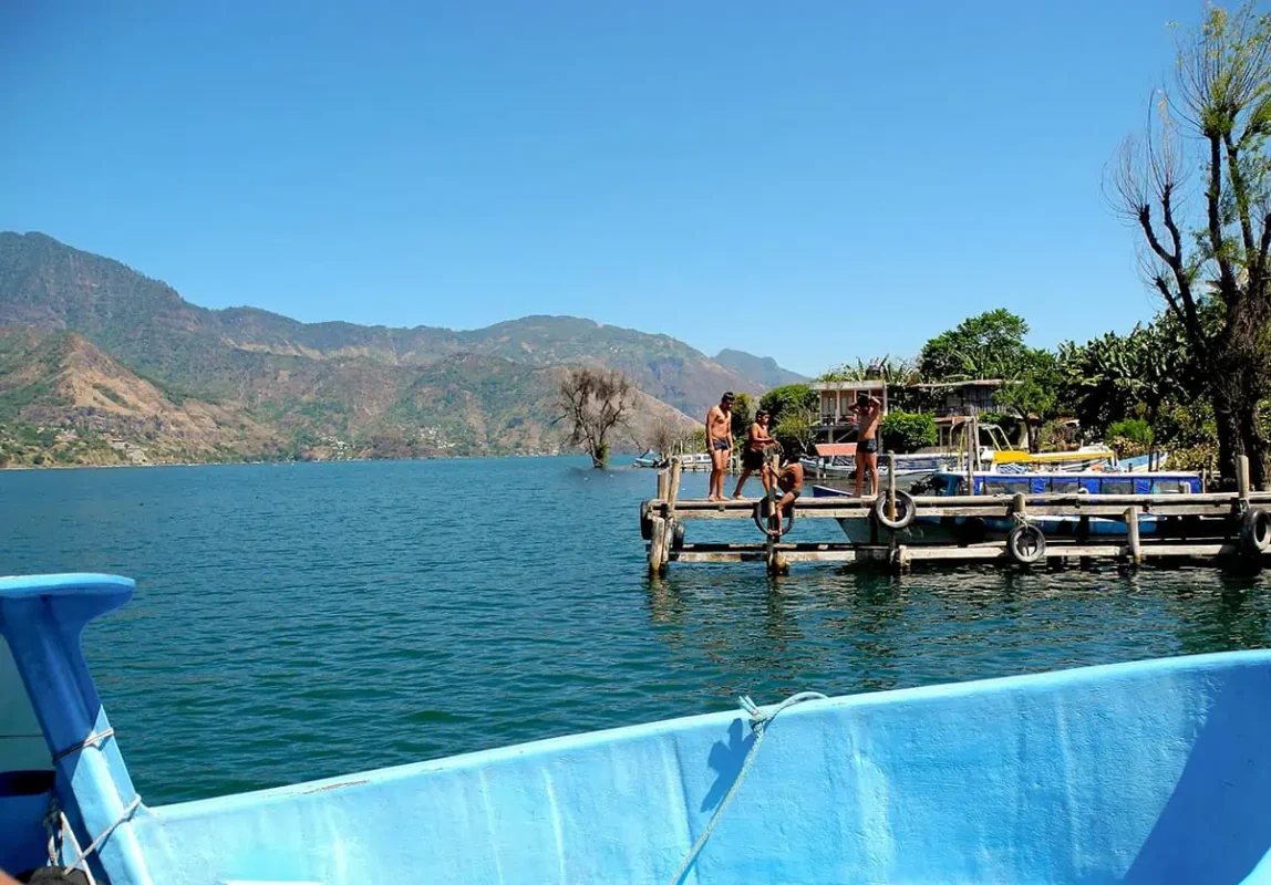Can You Swim In Lake Atitlan Guatemala? The Water Quality, Sicknesses, & Sewage 4 tourists jumping off one of the piers around lake atitlan in the questionable waters