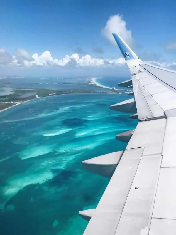 Cancun To Caye Caulker: The 4 Easiest Ways To Travel 6 Aerial view from a plane window showcasing the turquoise waters and sandy coastline when flying out of cancun