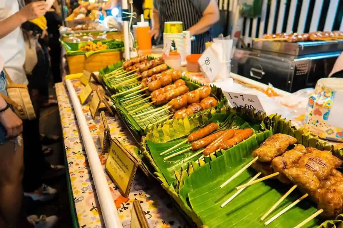 Chiang Mai Sunday Night Market: BEST Tips & Guide (2025) 19 A variety of grilled sausages on banana leaves, showcased at a food stall in the Chiang Mai Sunday market