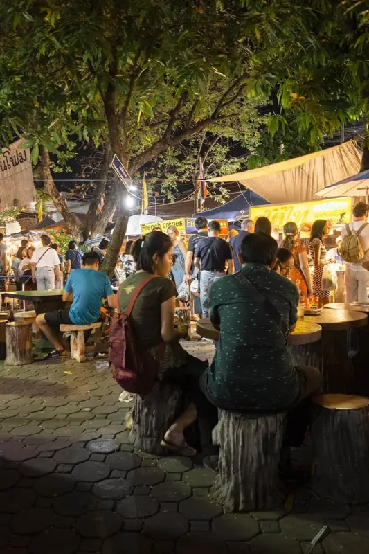 Chiang Mai Sunday Night Market: BEST Tips & Guide (2025) 22 Patrons enjoying street food under trees at the Sunday market in Chiang Mai