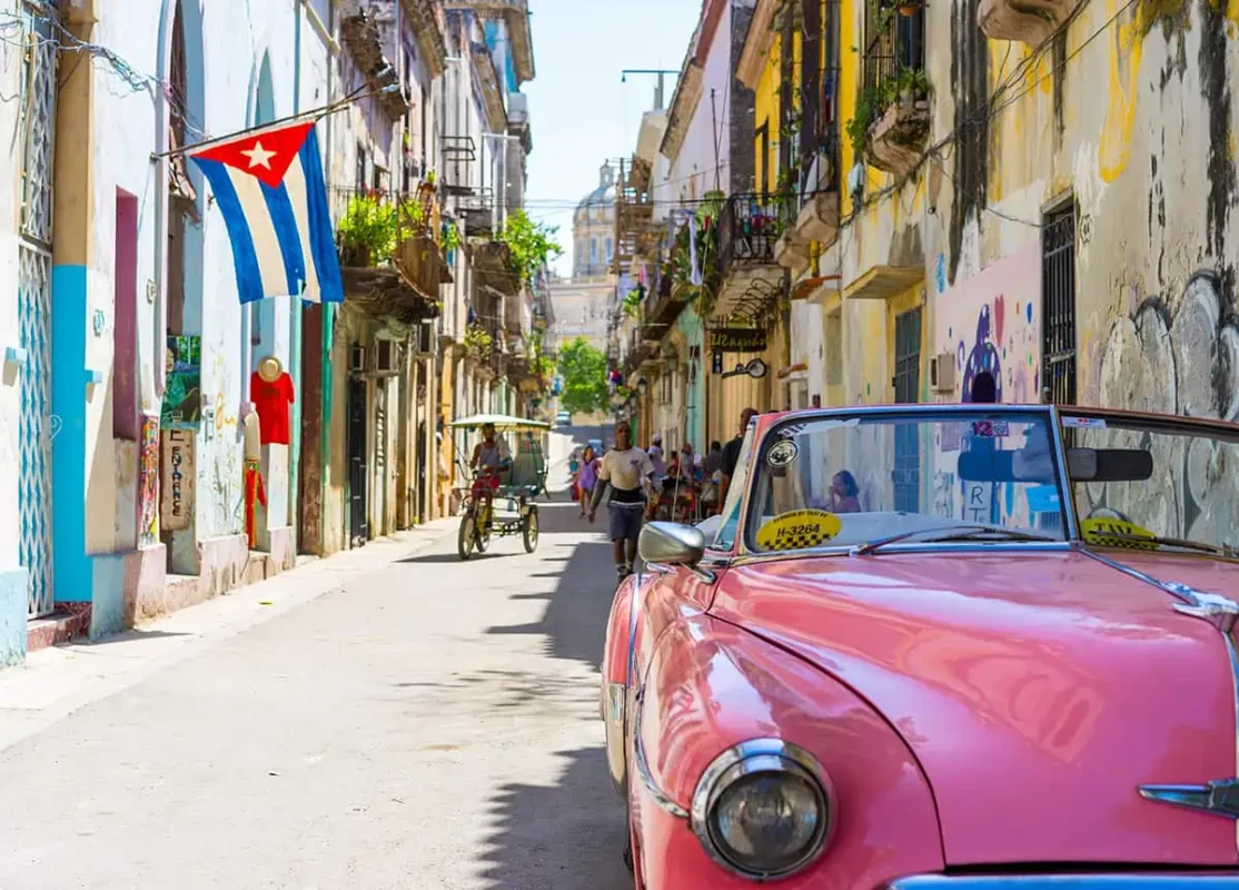 22+ Cheapest Countries To Backpack In The World! (2025) 23 A classic pink car is parked on a narrow street in havana.