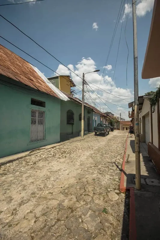 Flores To Belize City: Bus, Shuttle, Or Flight? (2025) 4 A quiet cobblestone street in Flores, lined with colorful houses and tangled overhead wires. The scene captures the rustic charm and tranquility of this small town.
