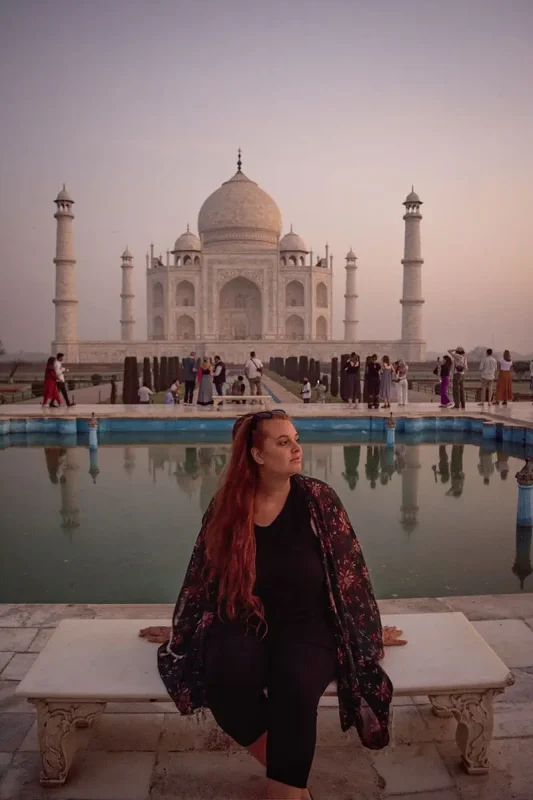 22+ Cheapest Countries To Backpack In The World! (2025) 19 A woman sitting on a bench in front of the taj mahal.