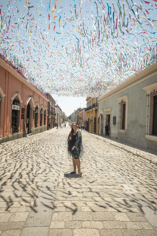 22+ Cheapest Countries To Backpack In The World! (2025) 25 tasha amy standing in the middle of a cobblestone street with colorful streamers hanging above her