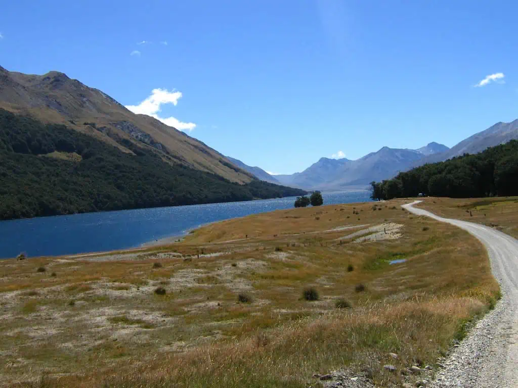 Fiordland & Milford Sound Lord Of The Rings Locations (2025) 8 A winding gravel road curves past Mavora lake toward distant mountains, one of the lord of the rings filming locations in fiordland