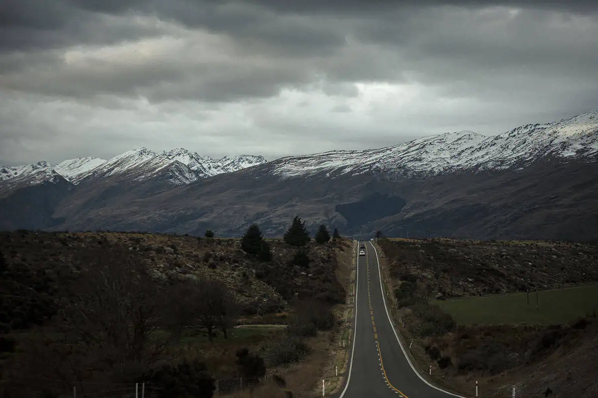 Fiordland & Milford Sound Lord Of The Rings Locations (2025) 11 A long straight road leads into a valley of rugged mountains dusted with snow in fiordland