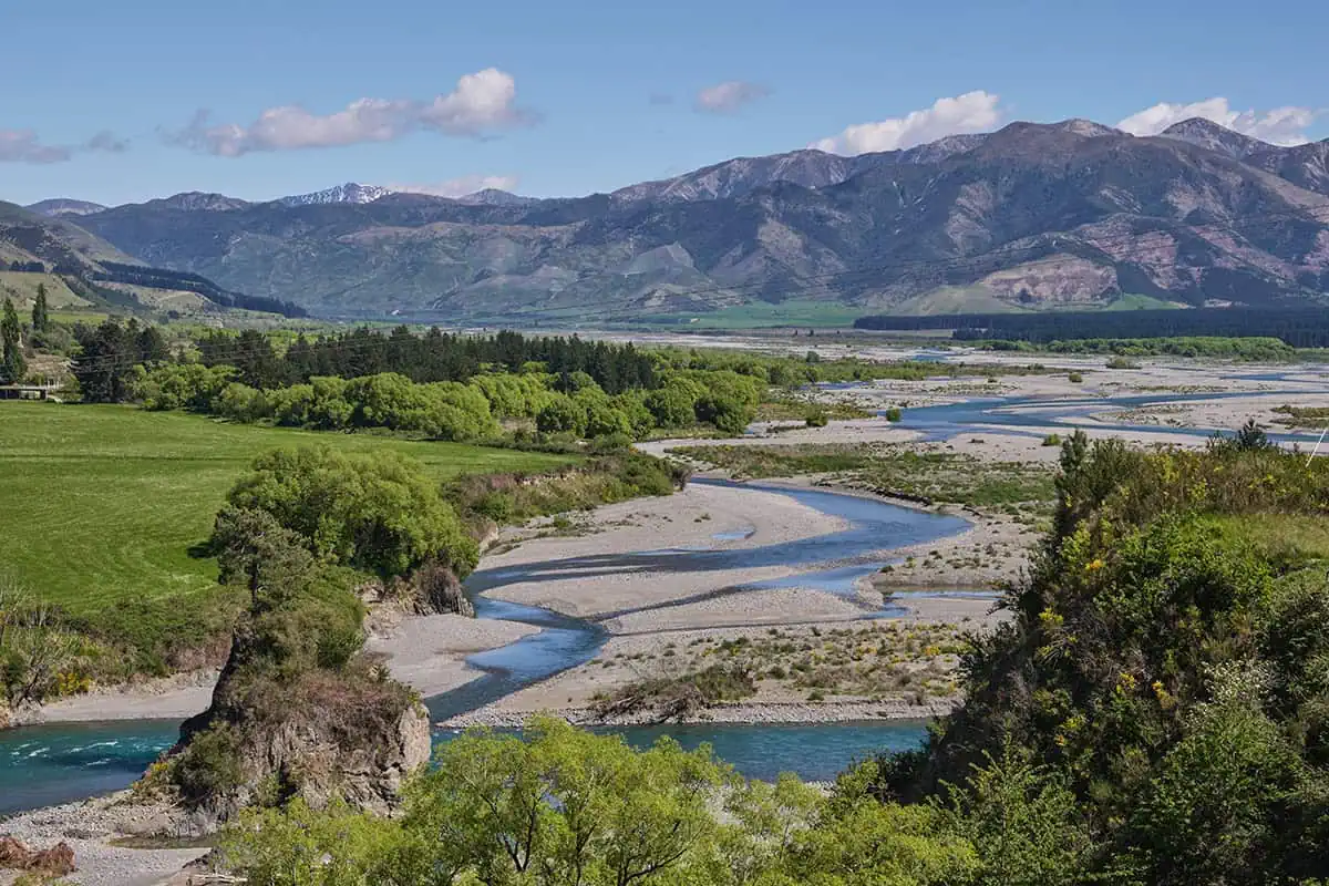 Fiordland & Milford Sound Lord Of The Rings Locations (2025) 10 A braided Waiau River winds through fields and rocky banks with mountains rising in the background