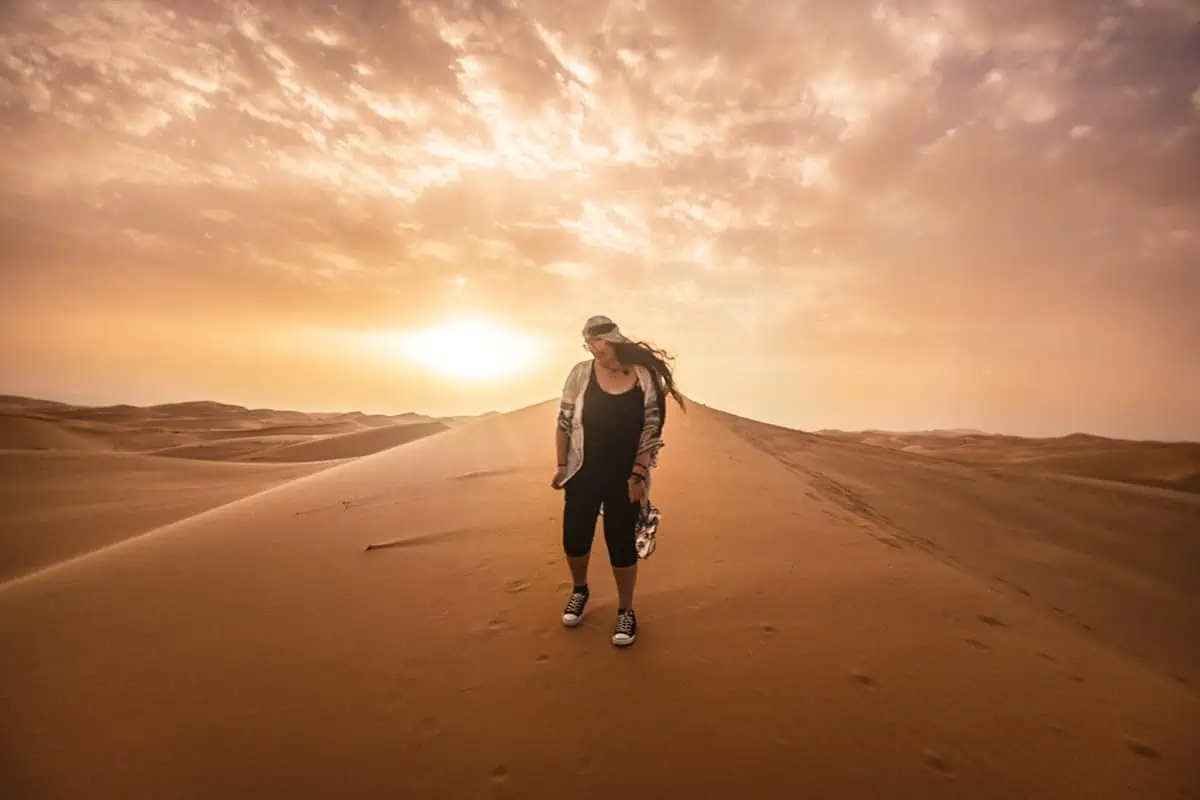 22+ Cheapest Countries To Backpack In The World! (2025) 13 tasha amy standing on a sand dune at sunset in morocco