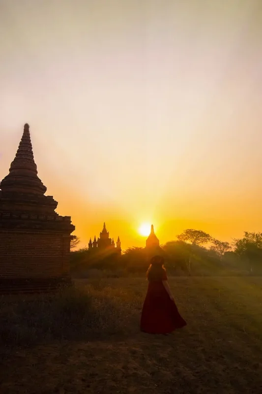 22+ Cheapest Countries To Backpack In The World! (2025) 17 tasha amy in a red dress walks through a field of pagodas at sunset.