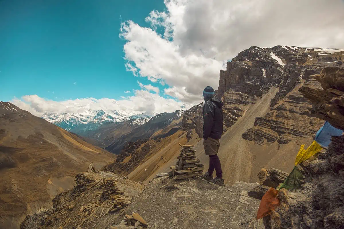 22+ Cheapest Countries To Backpack In The World! (2025) 10 A man standing on top of a rocky mountain on the annapurna circuit