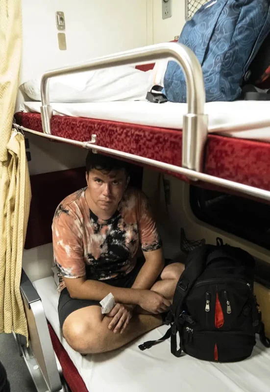 Sleeper Train Bangkok to Chiang Mai: BEST Tips 2025 14 A passenger looking unamused but comfortable in the lower berth of the sleeper train to Chiang Mai.